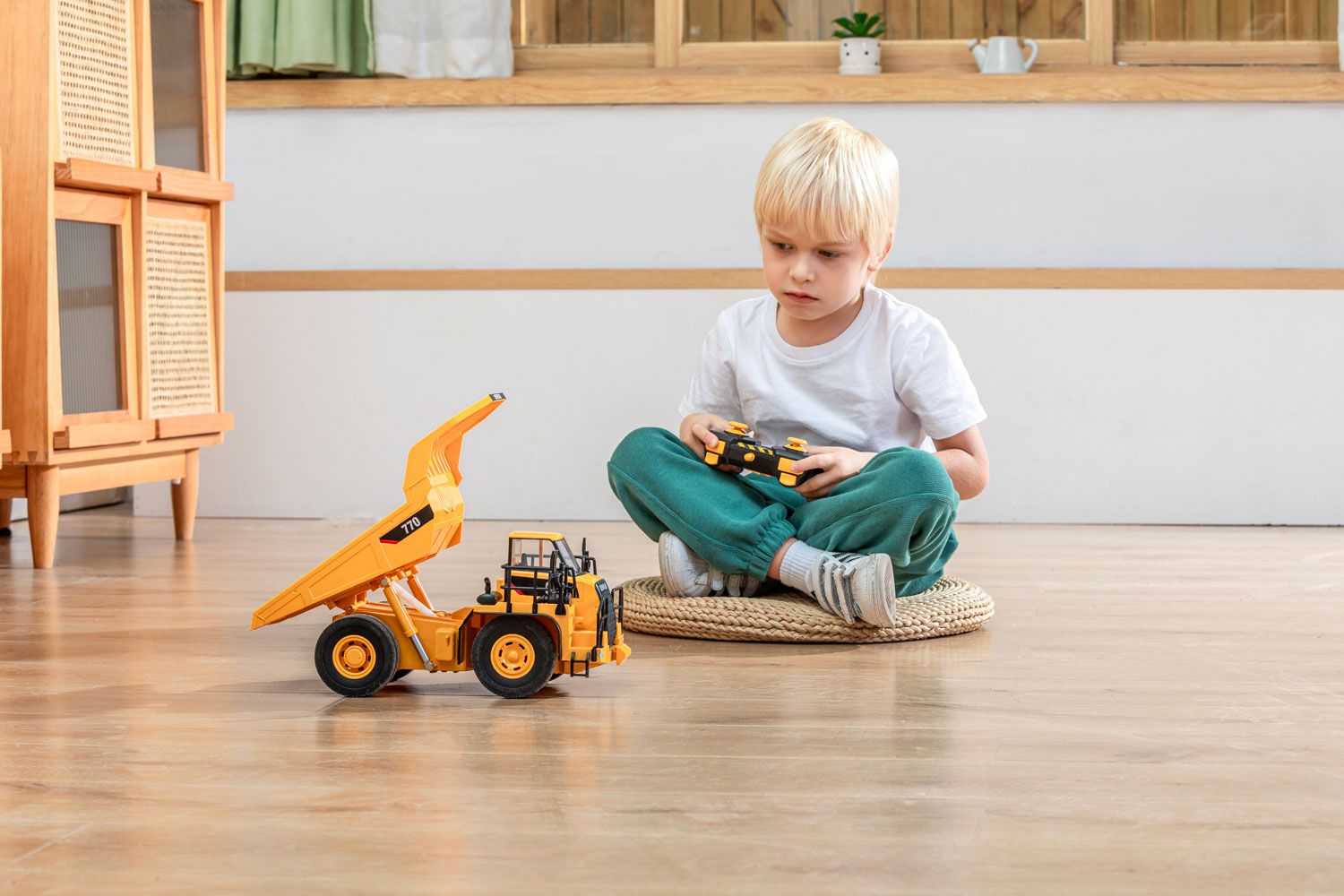 Child playing with a toy excavator on a hardwood floor inside a home, exemplifying indoor product photography.